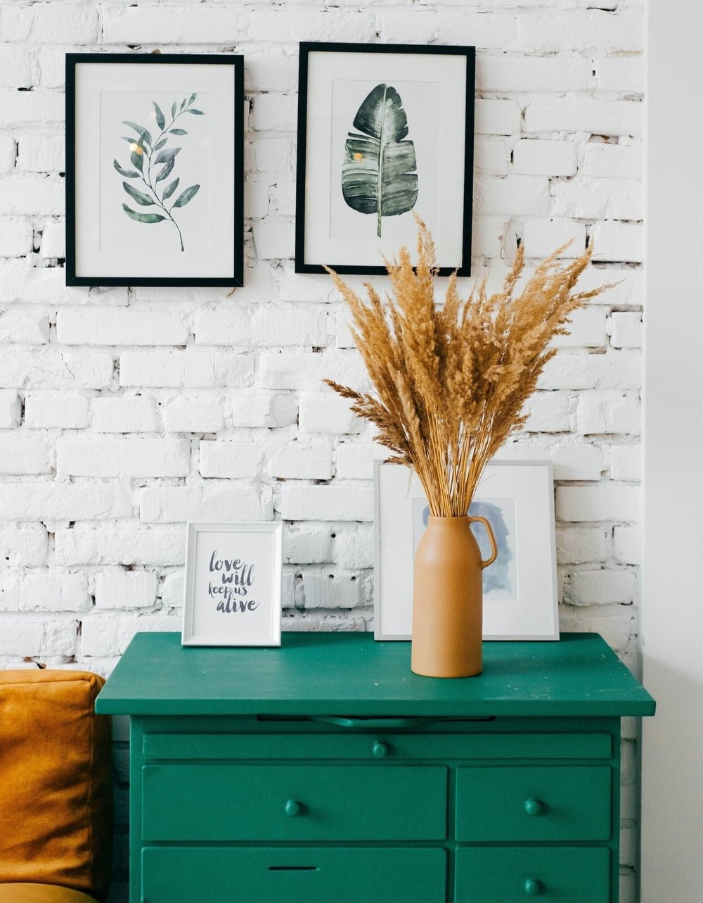 A calm, styled interior with framed botanical prints and dried grasses
